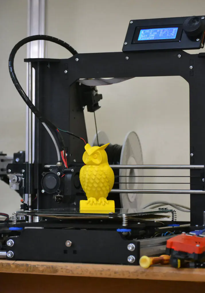 FDM printer with a finished yellow part on the bed